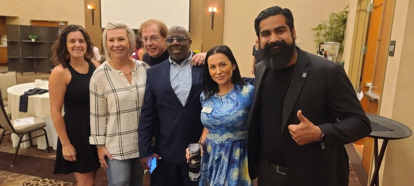 Five adults standing together at an evening community event