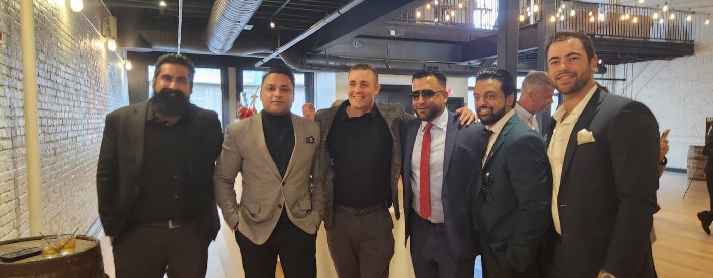 A group of men standing together for a photograph in a brick-walled event space