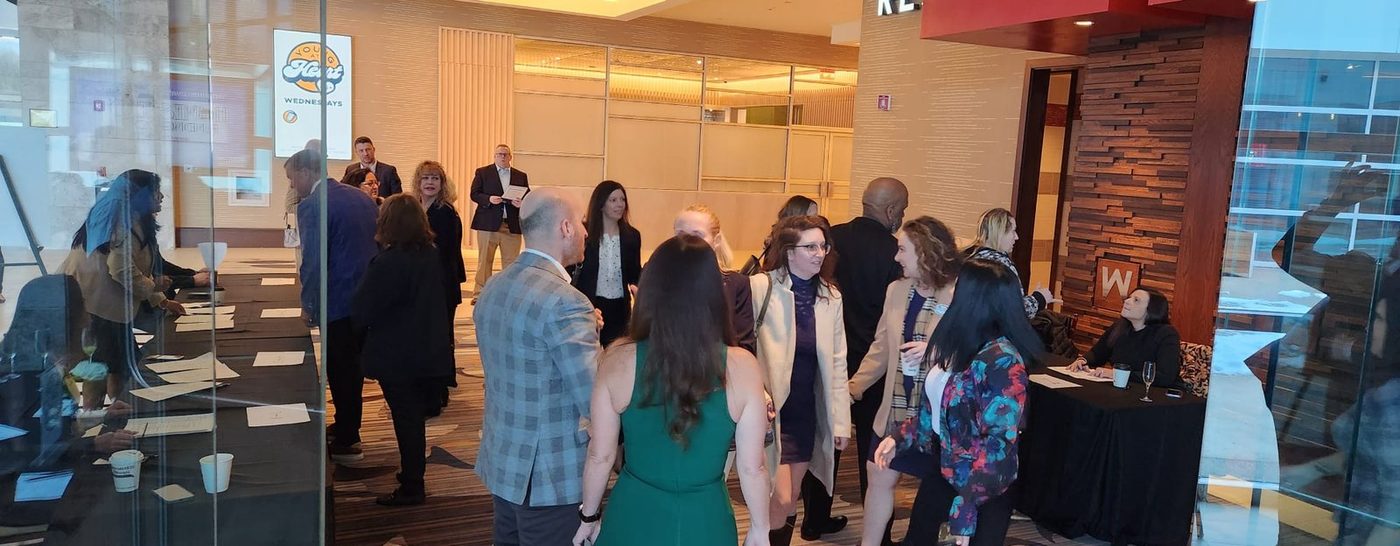 Attendees standing and talking in a bright glass-walled venue during a networking event