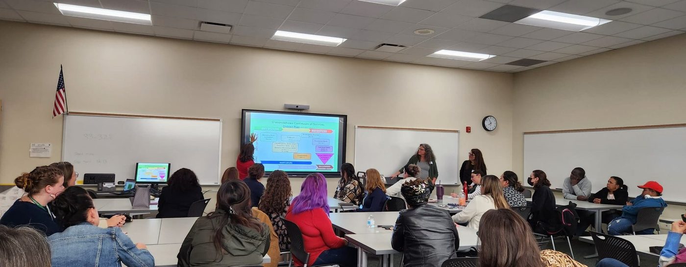 Parents and school staff seated in a classroom facing a presentation screen