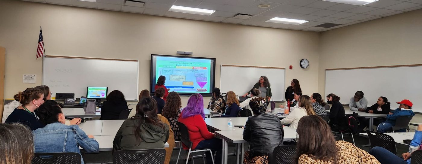 A classroom of attendees watching a special education presentation on a large screen